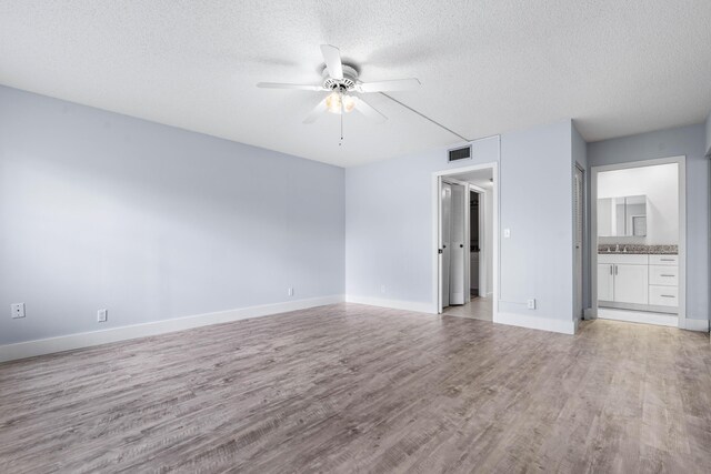 unfurnished room with a textured ceiling, light wood-type flooring, and ceiling fan