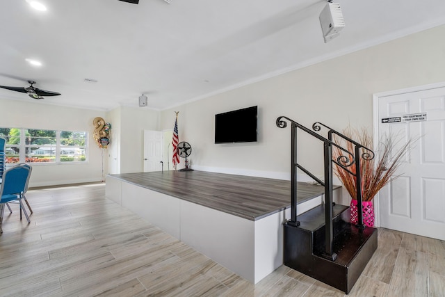 interior space featuring light wood-type flooring, ceiling fan, and crown molding