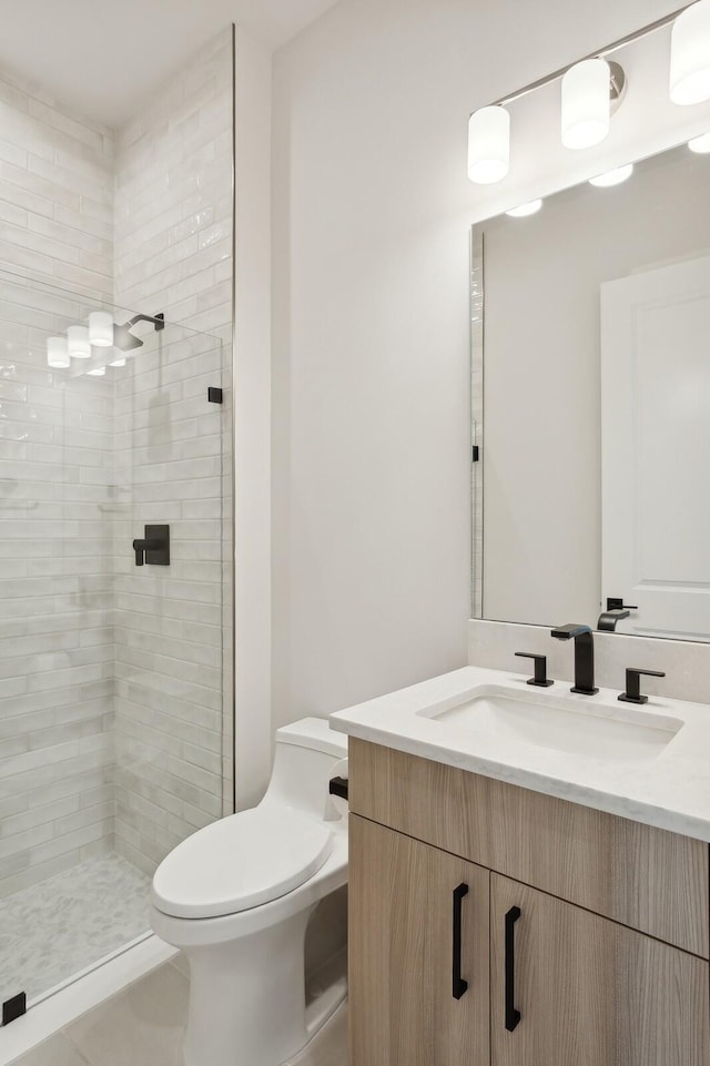 bathroom featuring tiled shower, vanity, and toilet