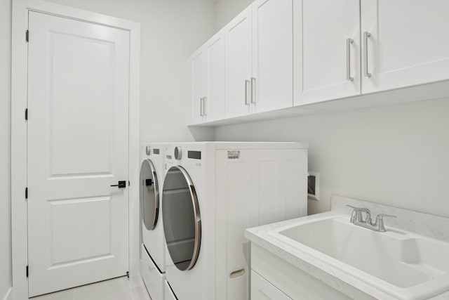 laundry room featuring cabinets, light tile patterned floors, sink, and washing machine and clothes dryer