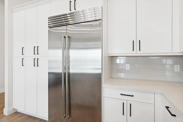 kitchen with backsplash, white cabinetry, stainless steel built in fridge, and light wood-type flooring