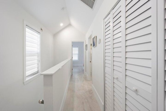 hallway with lofted ceiling and light hardwood / wood-style flooring