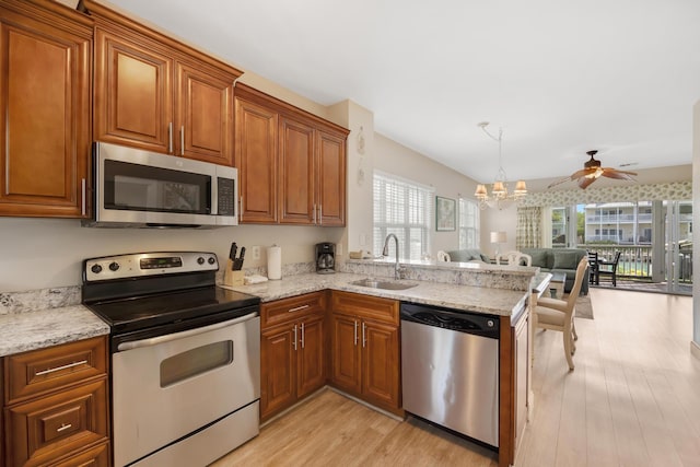 kitchen featuring appliances with stainless steel finishes, kitchen peninsula, sink, light hardwood / wood-style flooring, and ceiling fan with notable chandelier