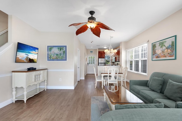 living room with ceiling fan with notable chandelier and light hardwood / wood-style floors