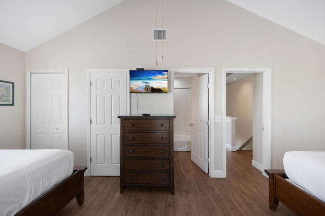 bedroom with ensuite bathroom, high vaulted ceiling, and dark hardwood / wood-style floors