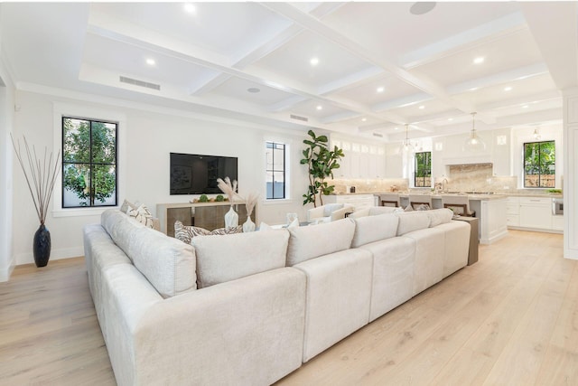 living room with light hardwood / wood-style floors, sink, beam ceiling, and coffered ceiling