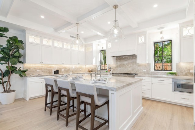 kitchen featuring light stone countertops, white cabinetry, and an island with sink