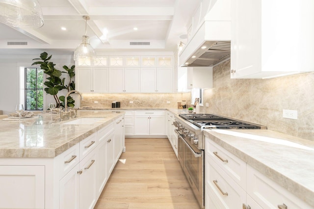 315 Avila Rd, West Palm Beach, FL 33405 - kitchen with high end stove, premium range hood, light wood finished floors, beamed ceiling, and white cabinets