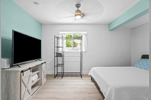 bedroom featuring ceiling fan, beamed ceiling, and light wood-type flooring