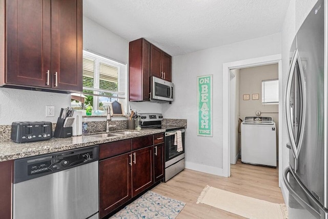 kitchen with sink, light wood-type flooring, a textured ceiling, stainless steel appliances, and washer / clothes dryer