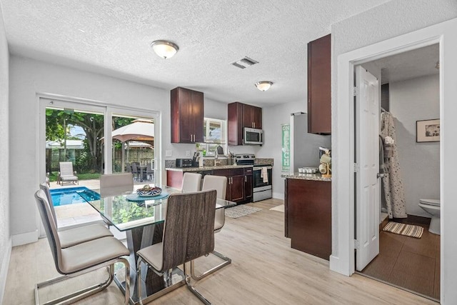 dining space featuring light hardwood / wood-style flooring, a textured ceiling, and sink