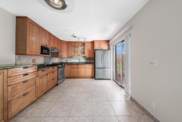 kitchen featuring appliances with stainless steel finishes, light tile patterned floors, ceiling fan, and decorative backsplash