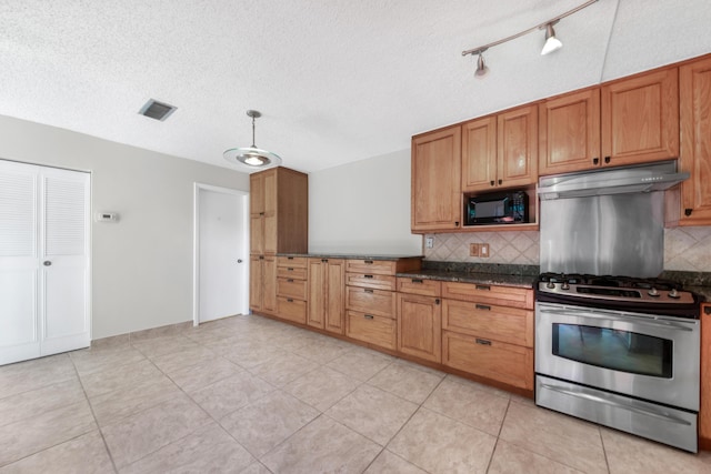 kitchen with light tile patterned floors, stainless steel gas range, dark stone countertops, backsplash, and black microwave