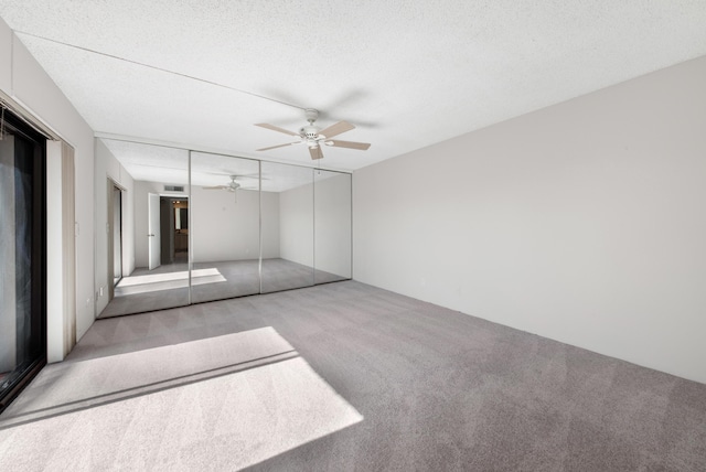 interior space featuring light colored carpet, a textured ceiling, ceiling fan, and a closet