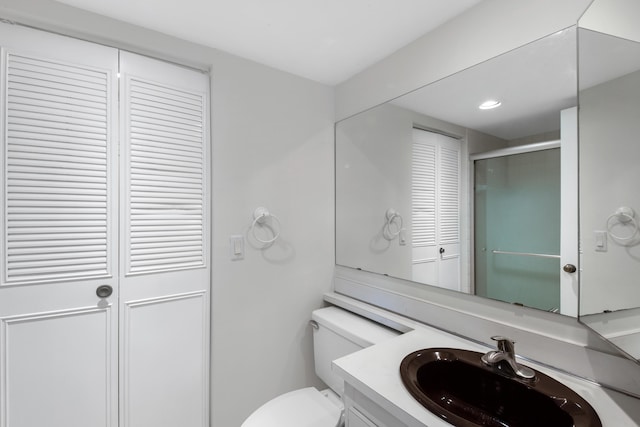 bathroom featuring vanity, toilet, and a shower with door