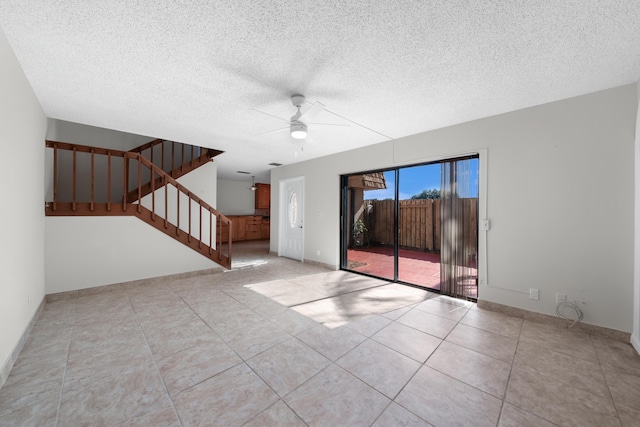 tiled empty room with ceiling fan and a textured ceiling