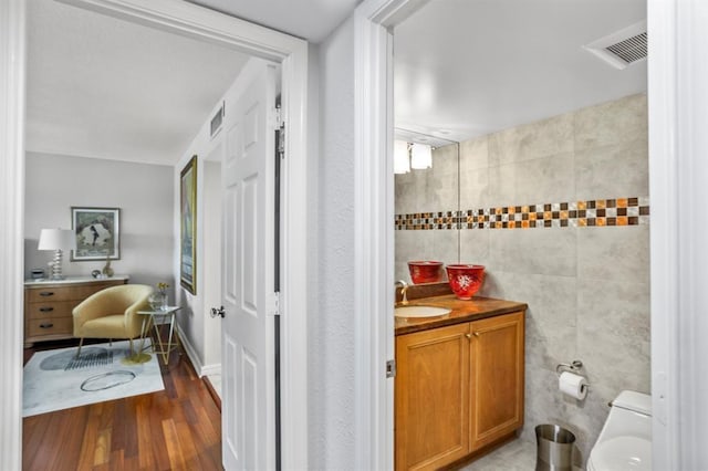 bathroom featuring hardwood / wood-style floors, vanity, toilet, and tile walls