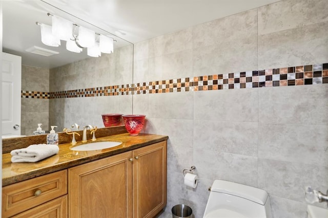 bathroom with vanity, toilet, and tile walls