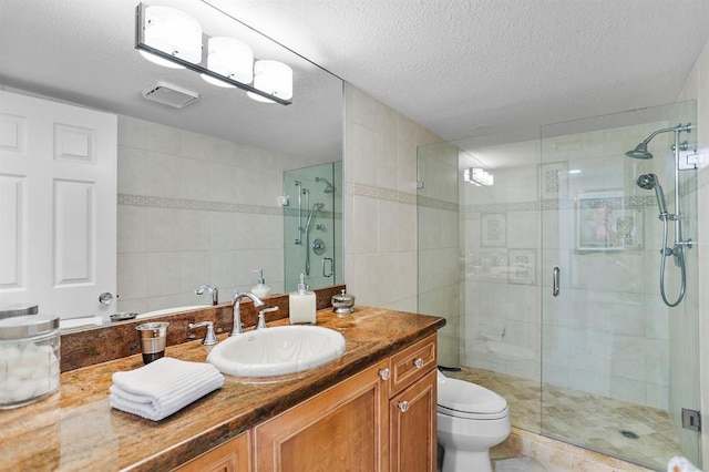 bathroom featuring vanity, a textured ceiling, a shower with door, tile patterned flooring, and toilet