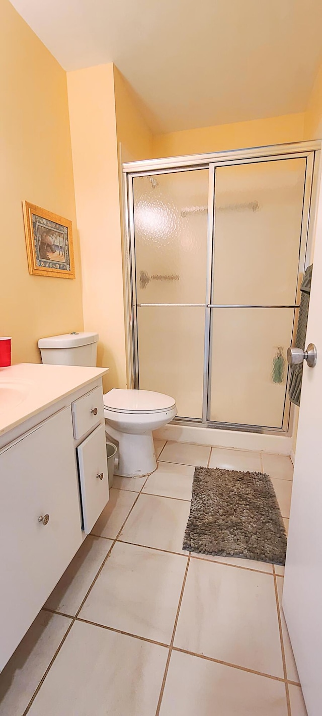 bathroom featuring tile patterned flooring, vanity, toilet, and walk in shower