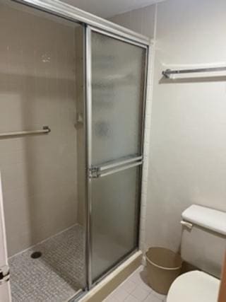 bathroom with tile patterned floors, a shower with shower door, and toilet