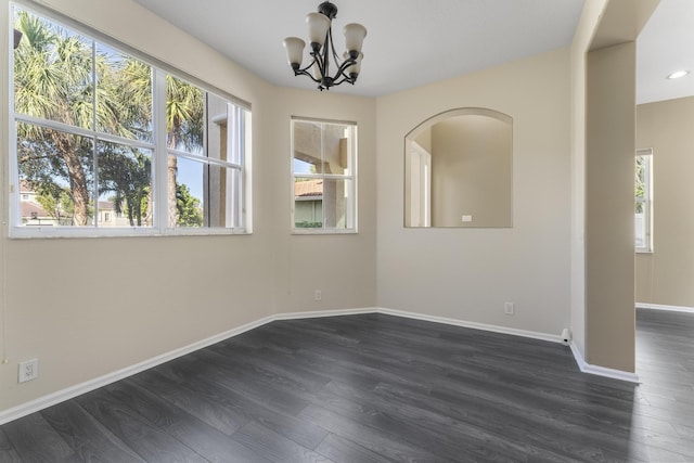 empty room with dark hardwood / wood-style flooring and a notable chandelier