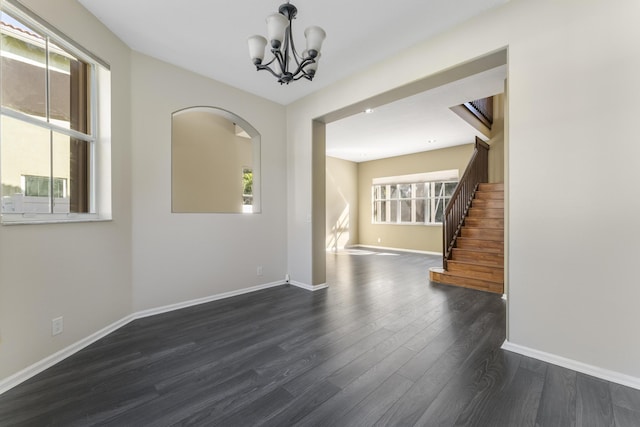 unfurnished room with dark wood-type flooring and a notable chandelier