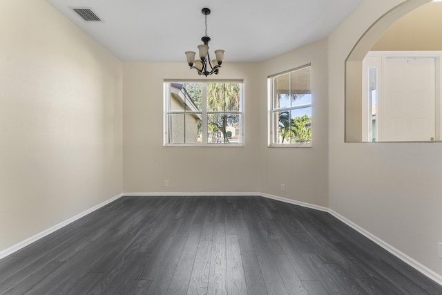 empty room with dark hardwood / wood-style floors and a chandelier