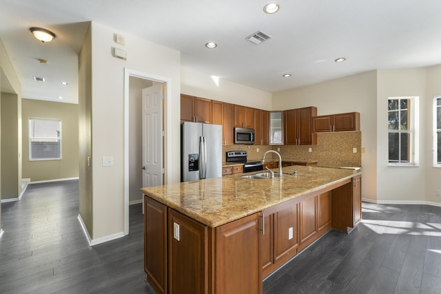 kitchen featuring stainless steel appliances, plenty of natural light, a center island with sink, and sink