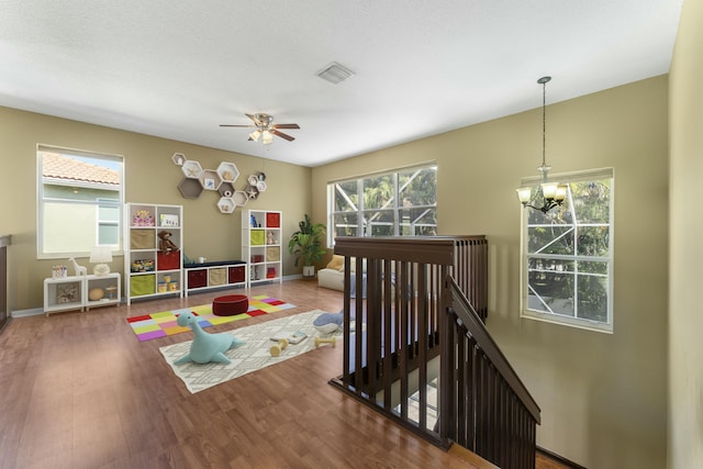 rec room featuring hardwood / wood-style floors and ceiling fan with notable chandelier