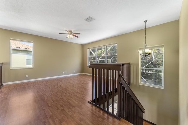 interior space with a textured ceiling, ceiling fan with notable chandelier, and dark hardwood / wood-style floors