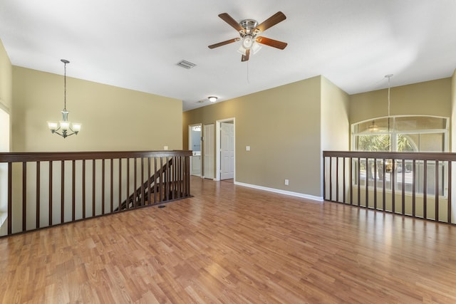 empty room with hardwood / wood-style floors and ceiling fan with notable chandelier