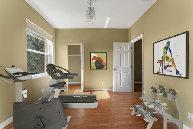 exercise room with hardwood / wood-style floors and an inviting chandelier