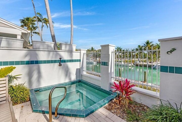 view of swimming pool with a water view and an in ground hot tub