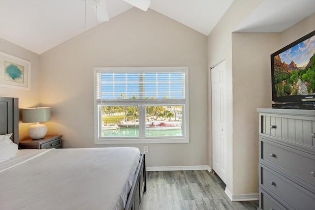 bedroom featuring light wood-type flooring, vaulted ceiling, a closet, and ceiling fan