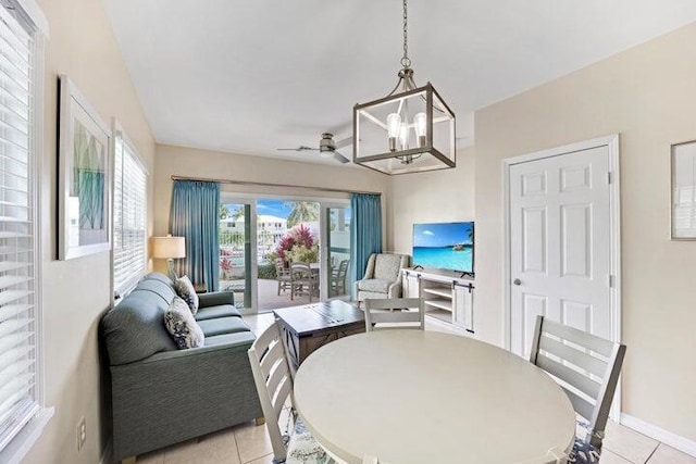 tiled dining space with ceiling fan with notable chandelier