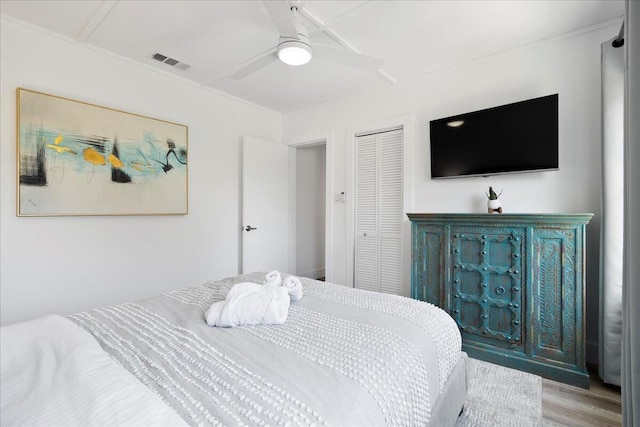 bedroom with ceiling fan, wood-type flooring, and a closet