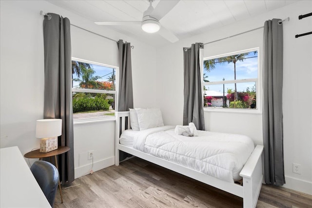 bedroom with ceiling fan, wood-type flooring, and multiple windows