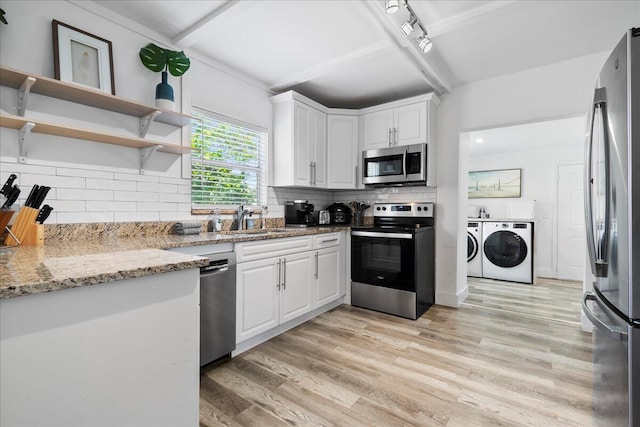 kitchen with sink, light stone countertops, separate washer and dryer, white cabinetry, and stainless steel appliances