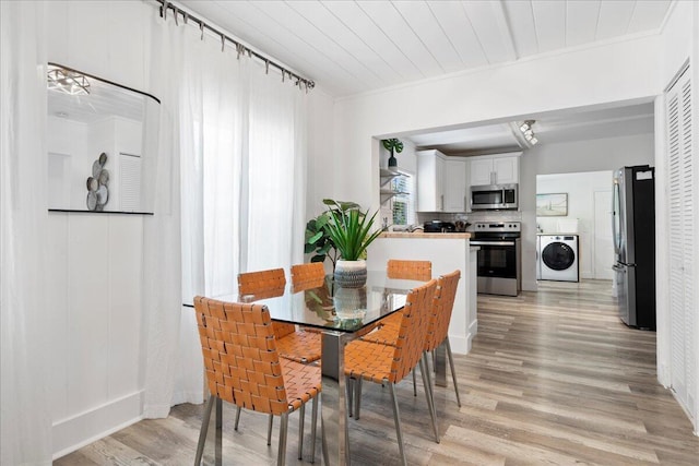 dining room featuring washer / dryer, light wood-type flooring, ornamental molding, and wooden ceiling