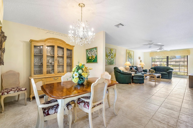 tiled dining room with a textured ceiling and ceiling fan with notable chandelier