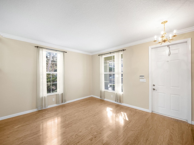 foyer with a chandelier, wood-type flooring, a textured ceiling, and ornamental molding