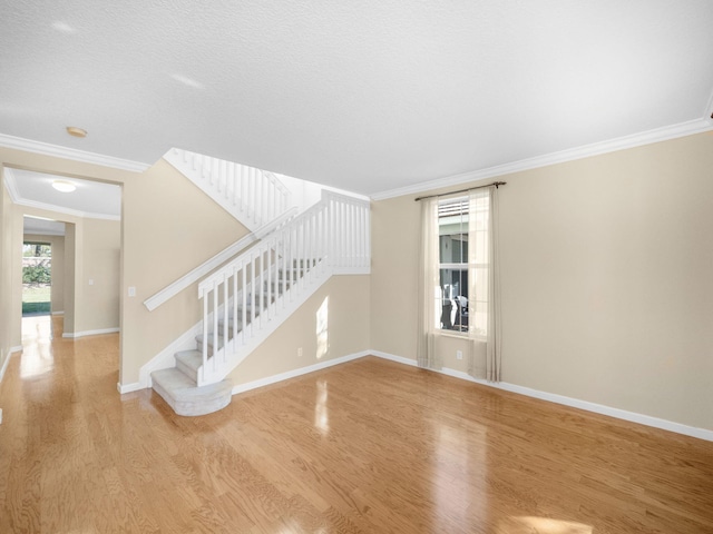 interior space with a textured ceiling, light hardwood / wood-style floors, and ornamental molding