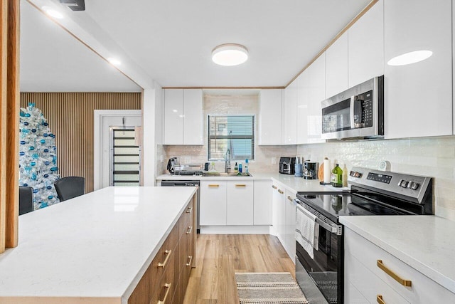 kitchen featuring backsplash, stainless steel appliances, sink, white cabinets, and light hardwood / wood-style floors