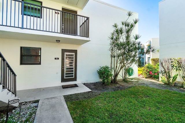 property entrance featuring a yard and a balcony