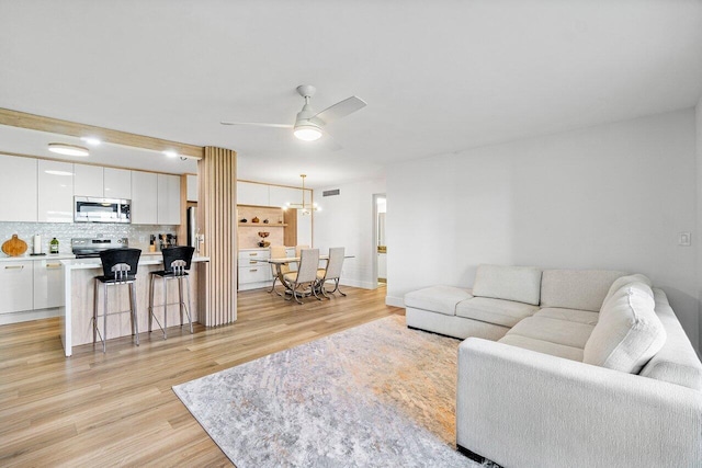 living room with light hardwood / wood-style flooring and ceiling fan