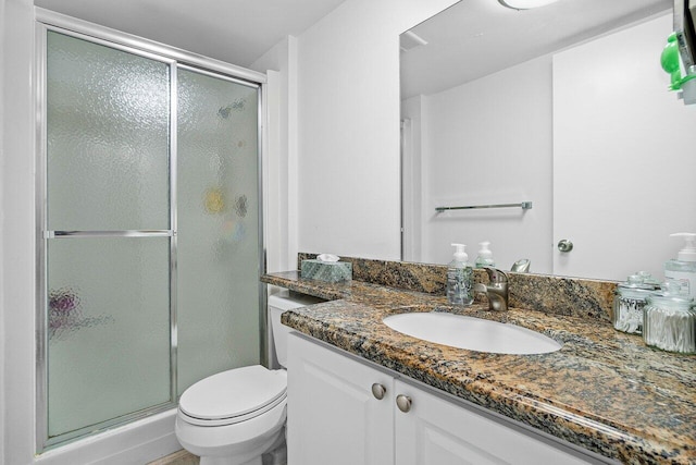 bathroom with a shower with door, vanity, and toilet