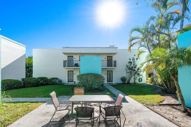 back of house with a lawn, a balcony, and a patio