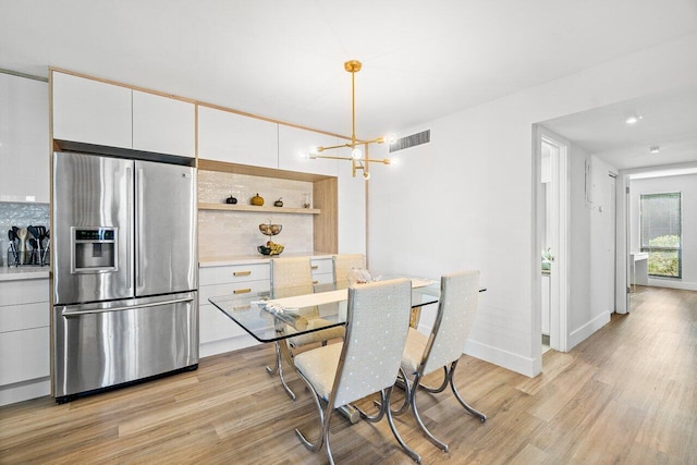 dining area featuring light wood-type flooring and a chandelier