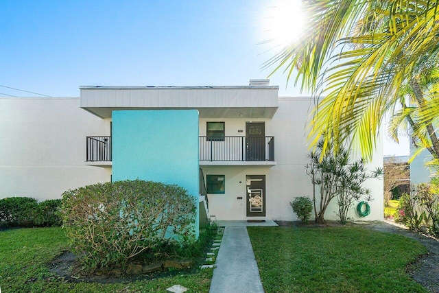 view of front of property with a front yard and a balcony